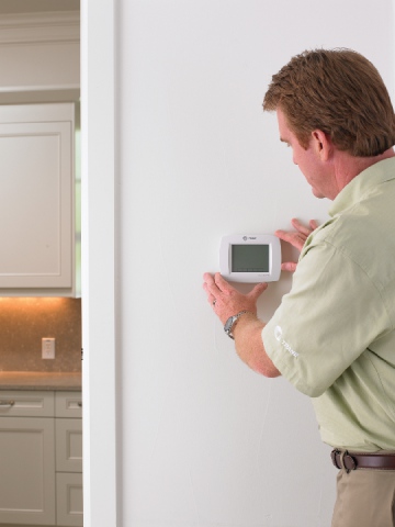 A technician looks at the thermostat in a Lewisville home