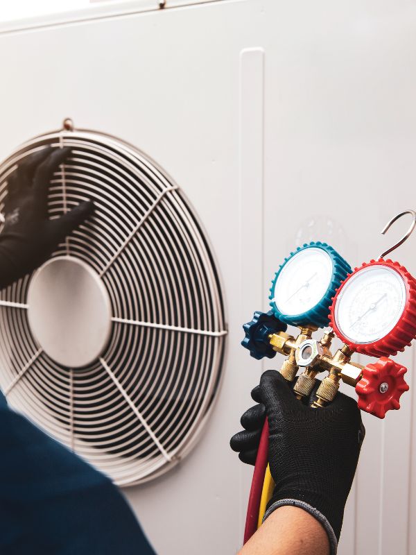 An HVAC Technician is working on an air conditioner.